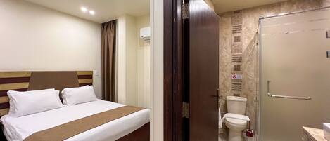 A hotel room with a bed, a shower, and a toilet.