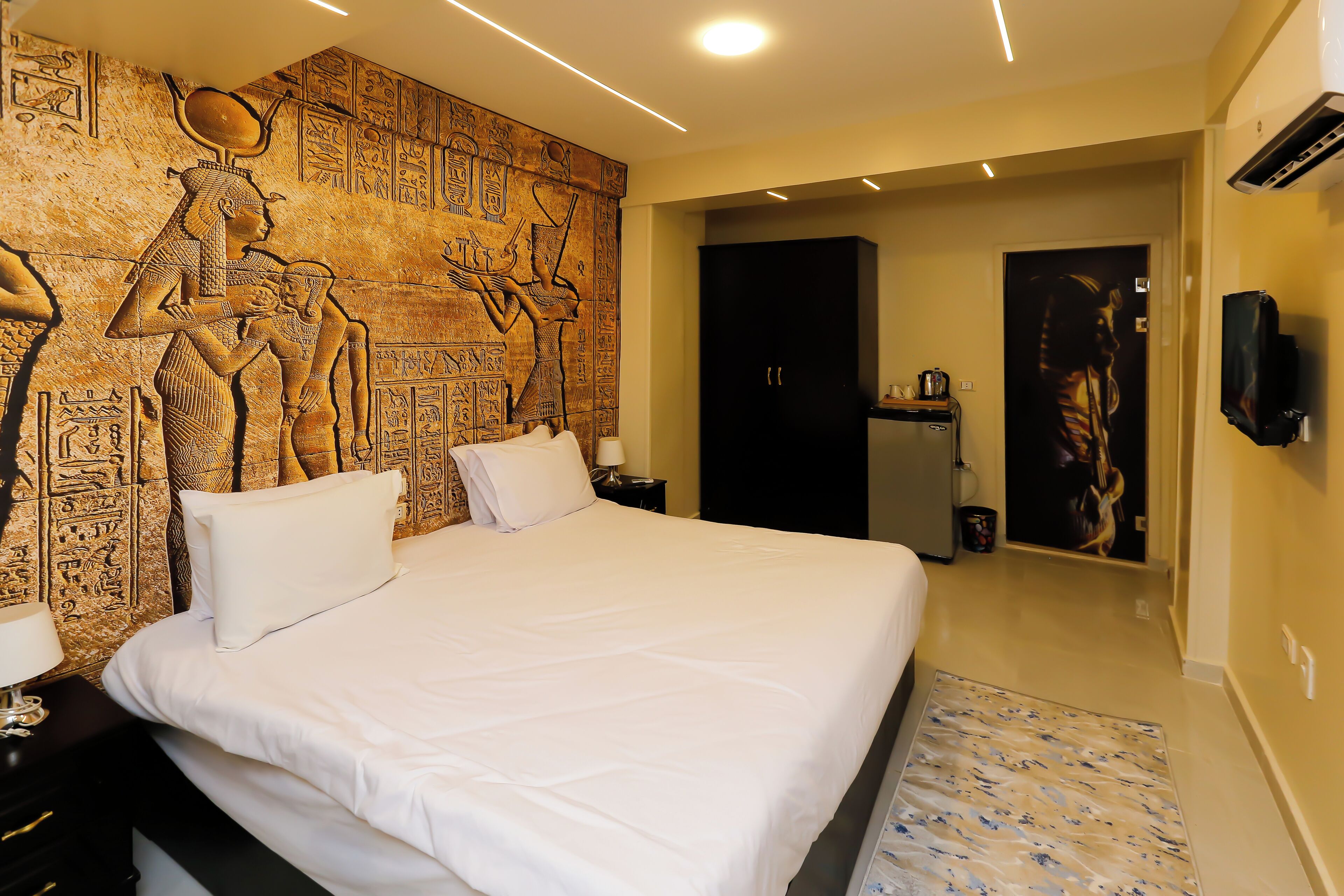 Een hotelkamer met een groot bed, een wanddecoratie, een flatscreen-tv en een deur naar een badkamer.