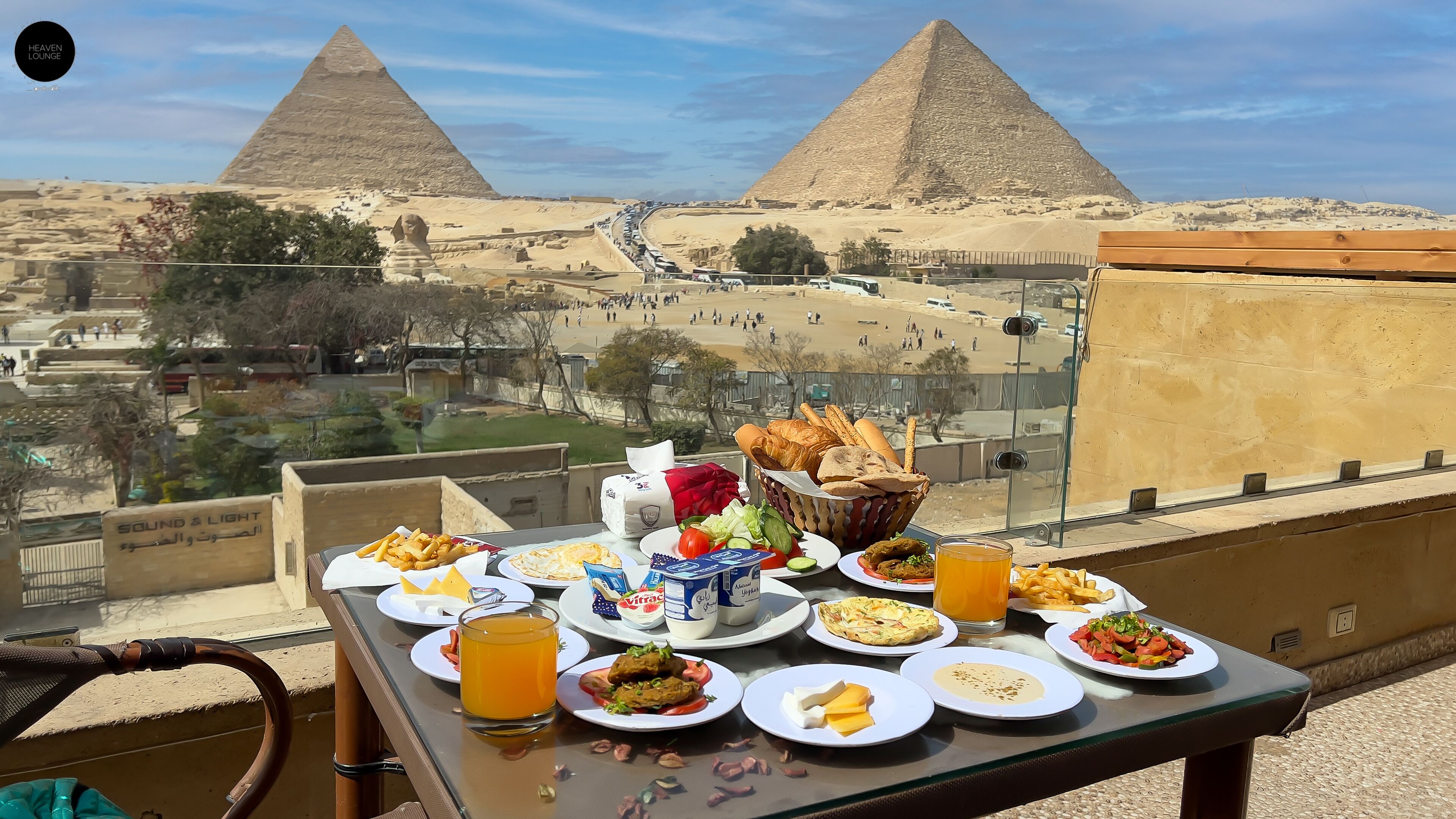 A table with various dishes and drinks, overlooking the pyramids.