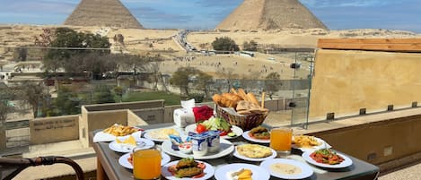 A table with various dishes and drinks, overlooking the pyramids.