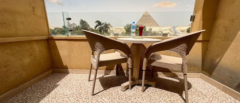 A balcony with a table and chairs, a water bottle, and a red drink on the table.