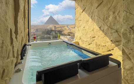 A hot tub with a view of a pyramid and desert landscape.