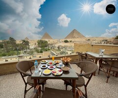 A table with food and drinks on a terrace overlooking pyramids.