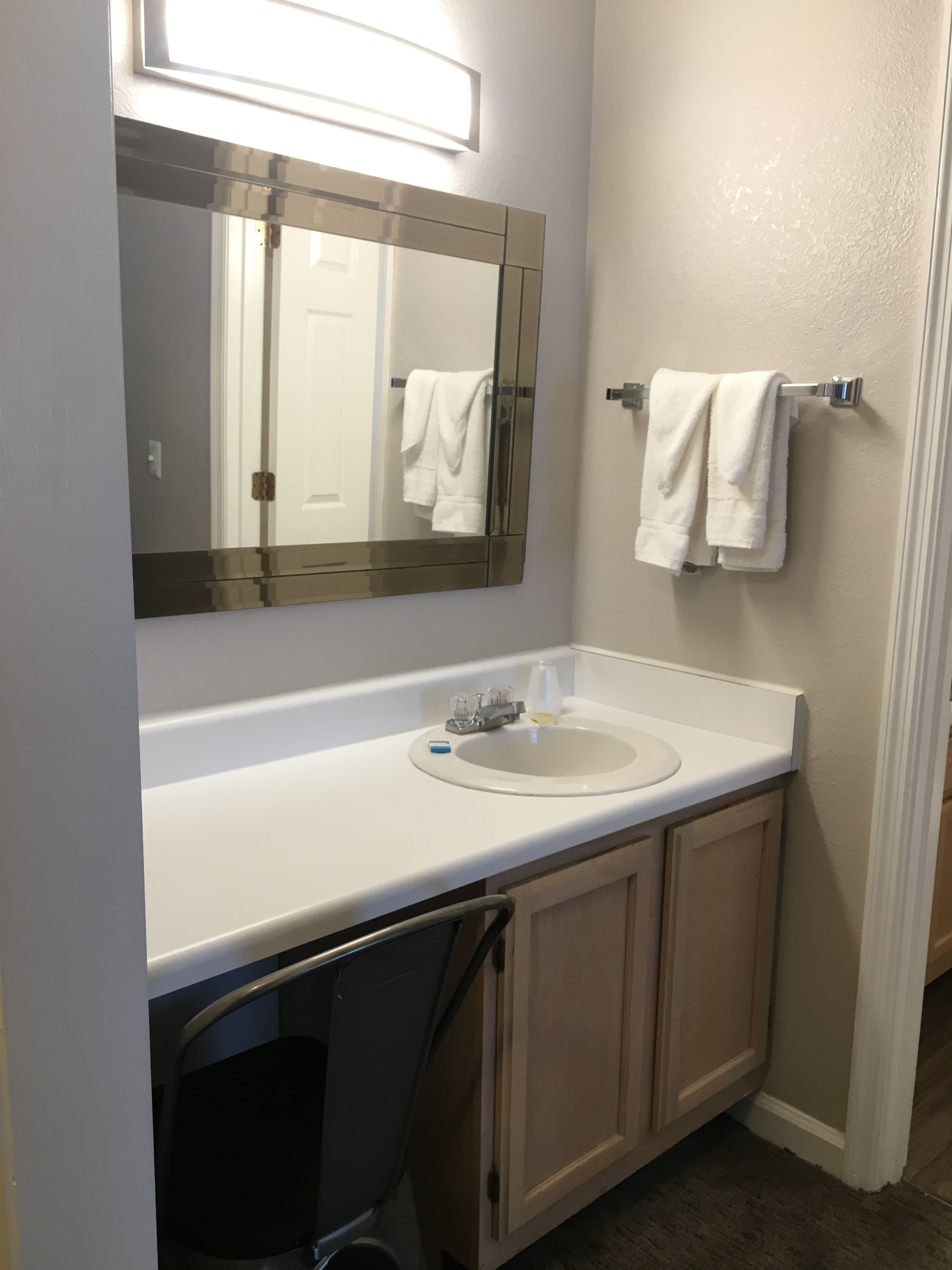A bathroom with a white sink, a mirror, and a towel rack.