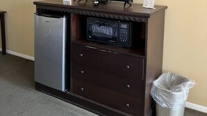 A minibar with a television, microwave, refrigerator, and a trash can. - Ambassador Inn And Suites (Manchester)