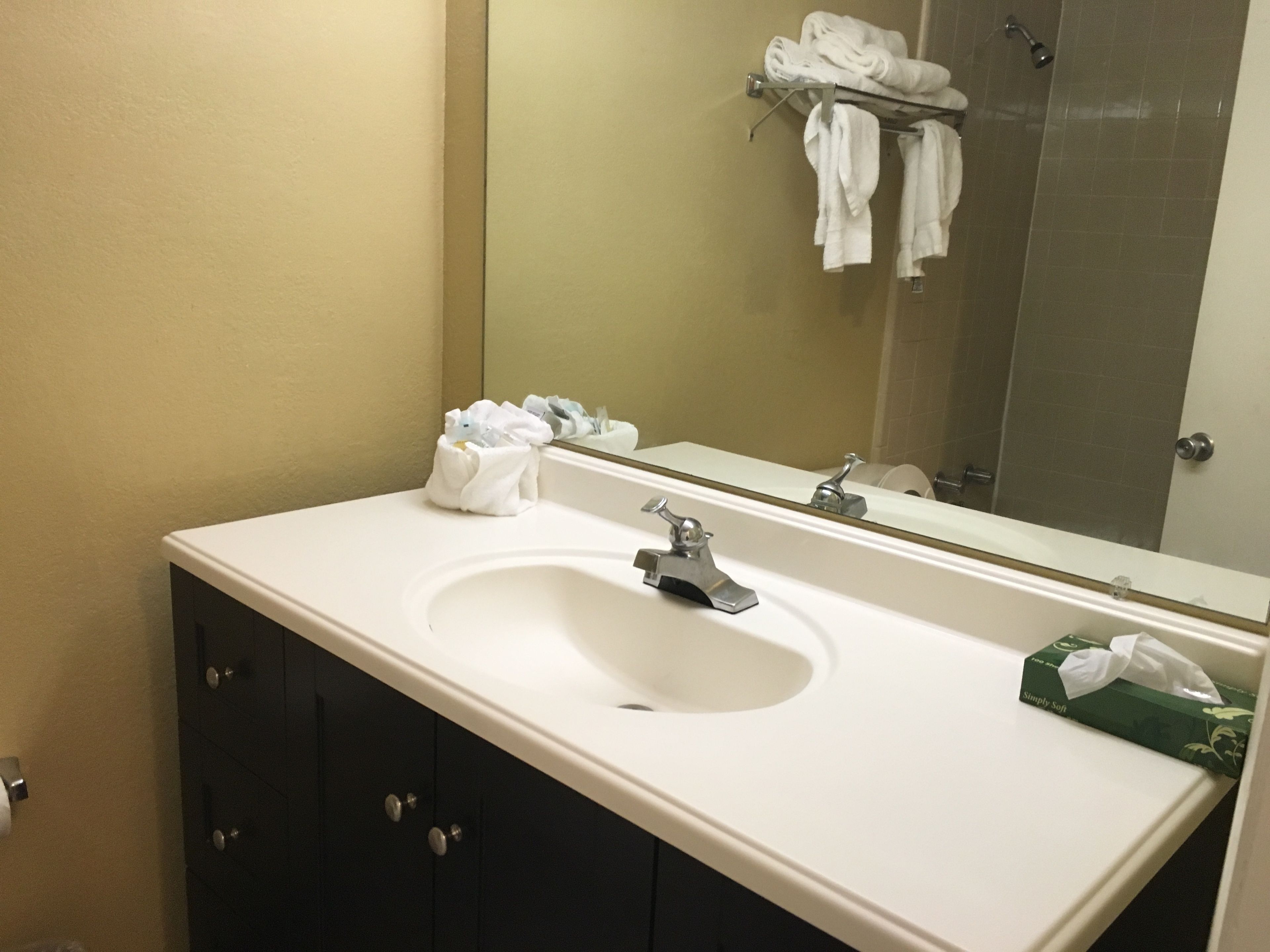 A bathroom with a white sink, a mirror, and a towel rack with towels.