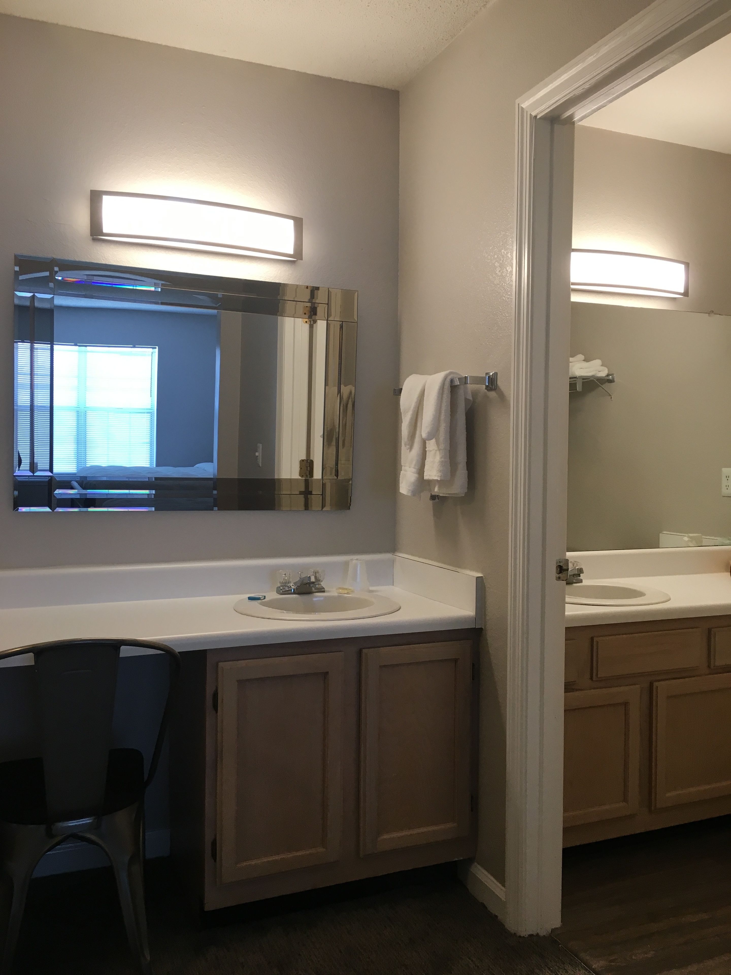 A bathroom with two sinks, a mirror, and a chair.