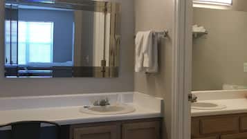 A bathroom with two sinks, a mirror, and a chair.