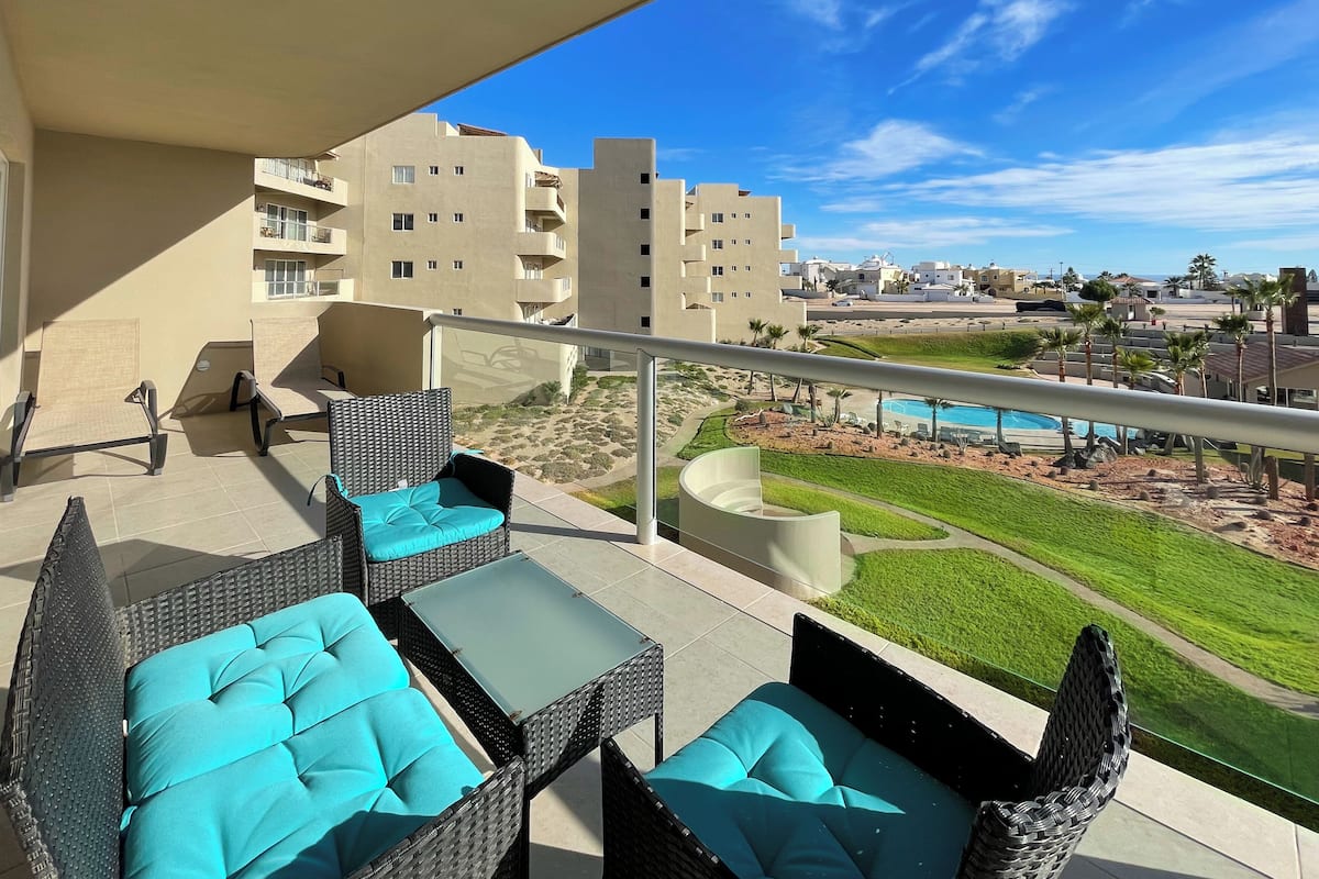 Un balcón con mobiliario de mimbre y vista a la piscina.
