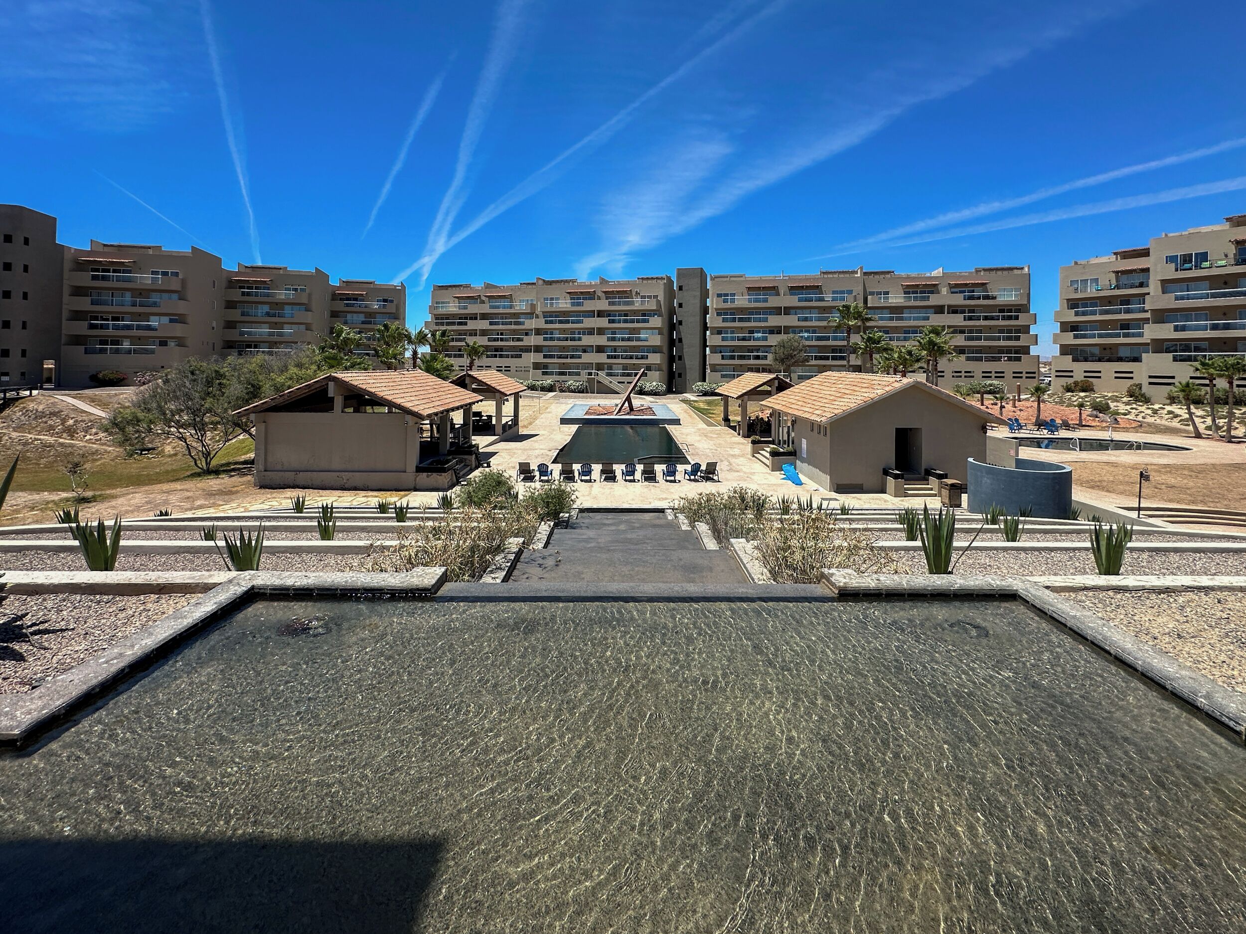 Ein Resort mit einem zentralen Pool, mehreren Gebäuden und Sitzbereichen im Freien.