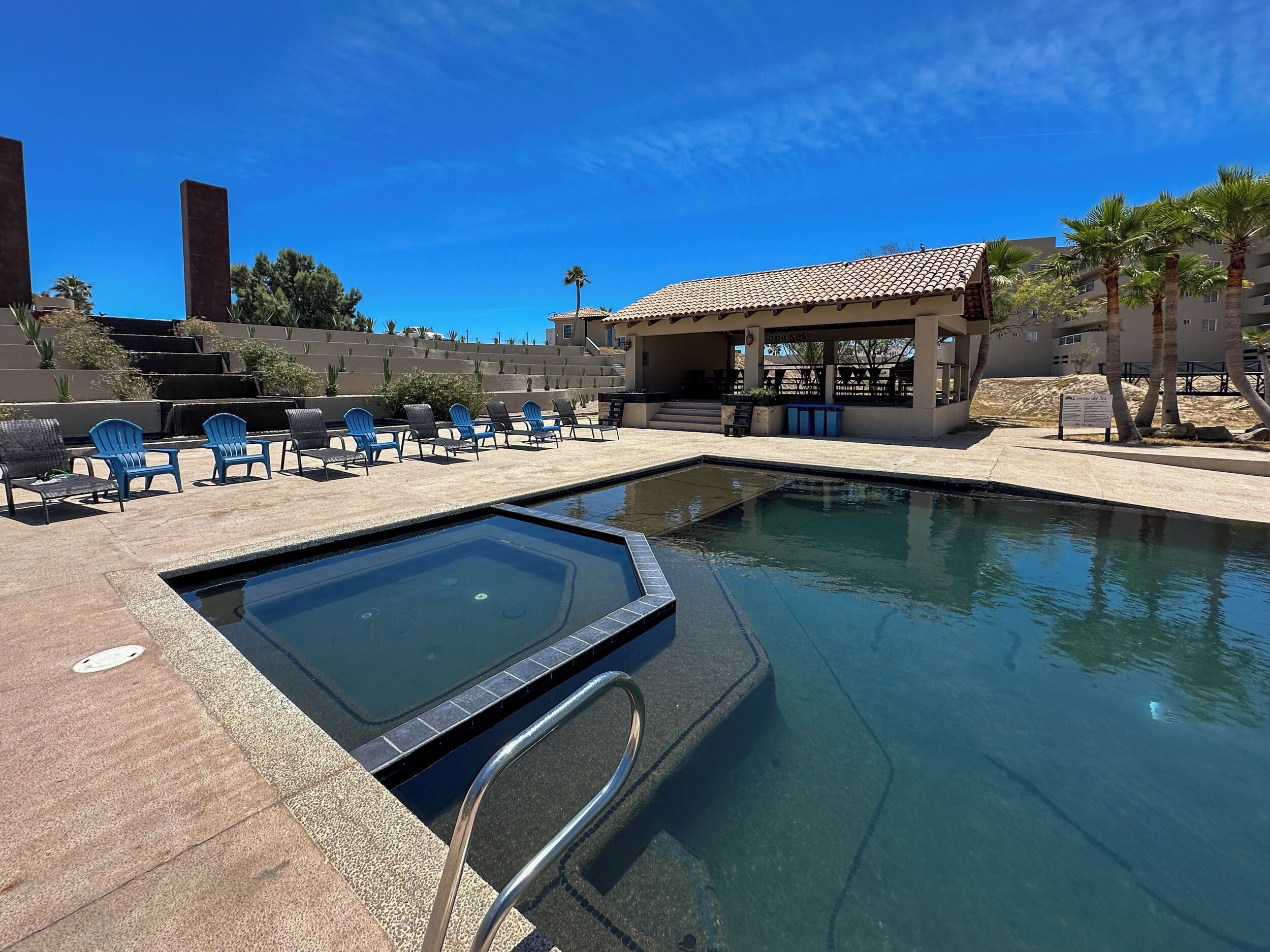 A swimming pool with lounge chairs and a covered seating area.