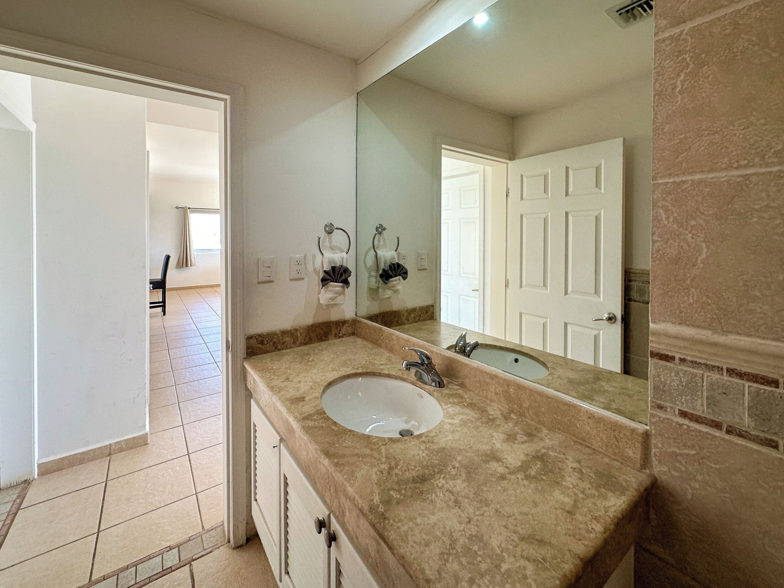 A bathroom with a sink, mirror, and towel rack.