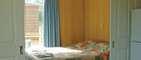 A bedroom with a bed, a window with curtains, and a door.