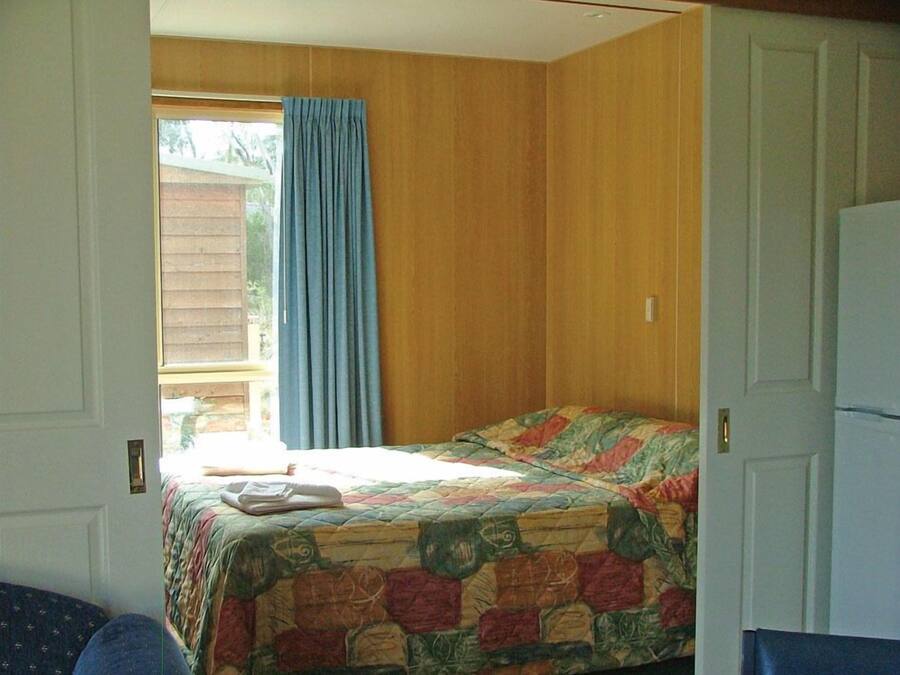 A bedroom with a bed, a window with curtains, and a door.