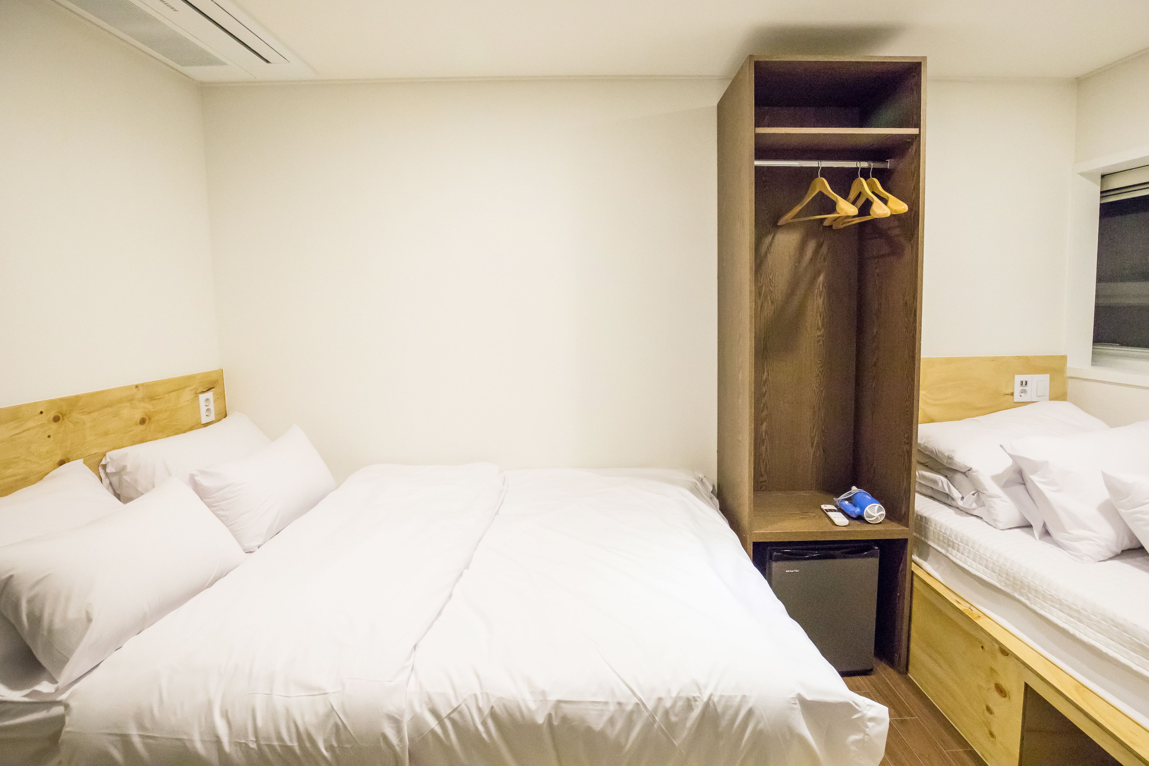 Une chambre d’hôtel avec un grand lit, une armoire en bois et un petit bureau équipé d’un réfrigérateur.