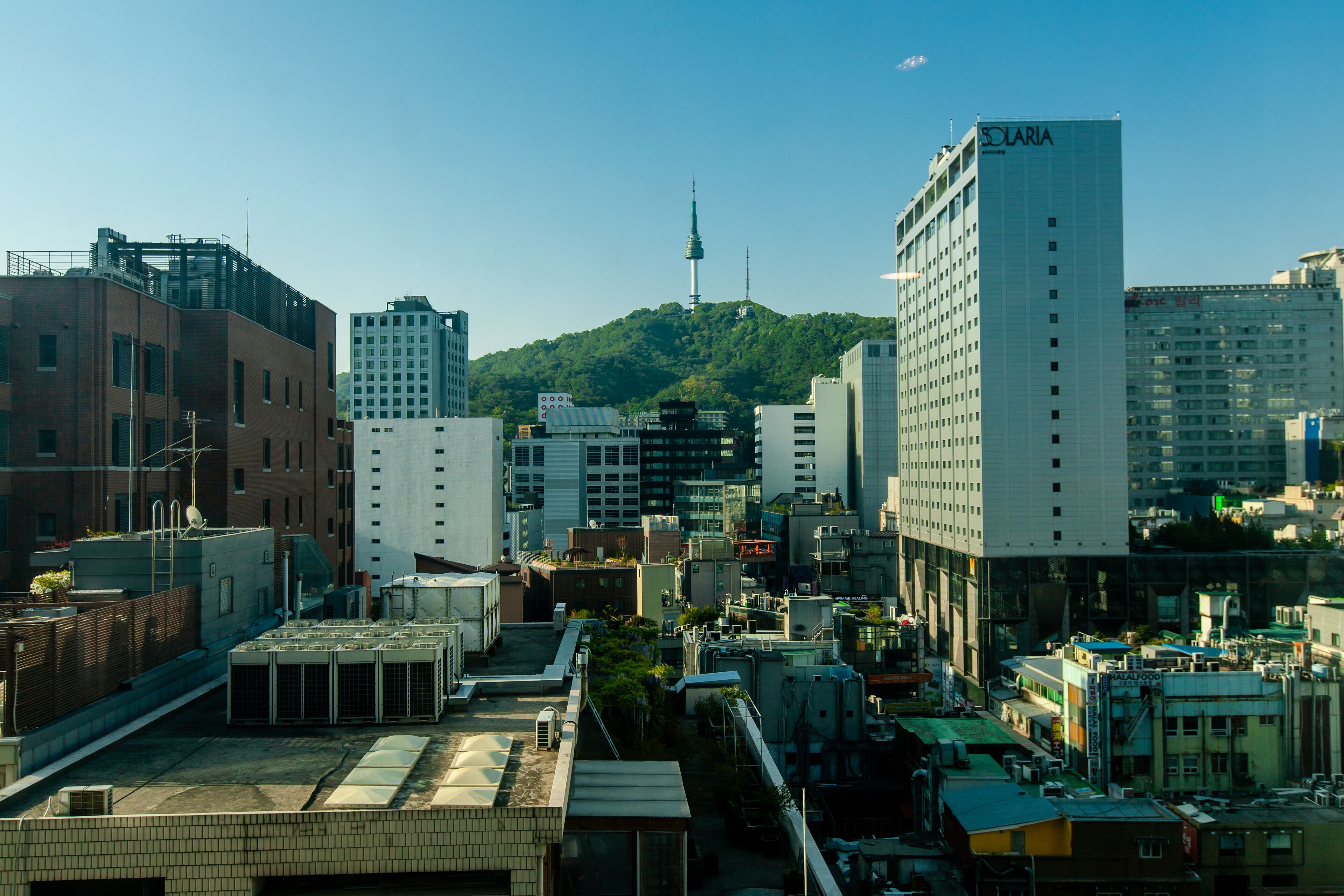A cityscape with modern buildings, including a prominent white building with 'SOLARIA' on it.