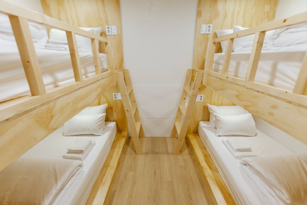 A cabin with two wooden bunk beds, each with a pillow and a neatly folded towel.