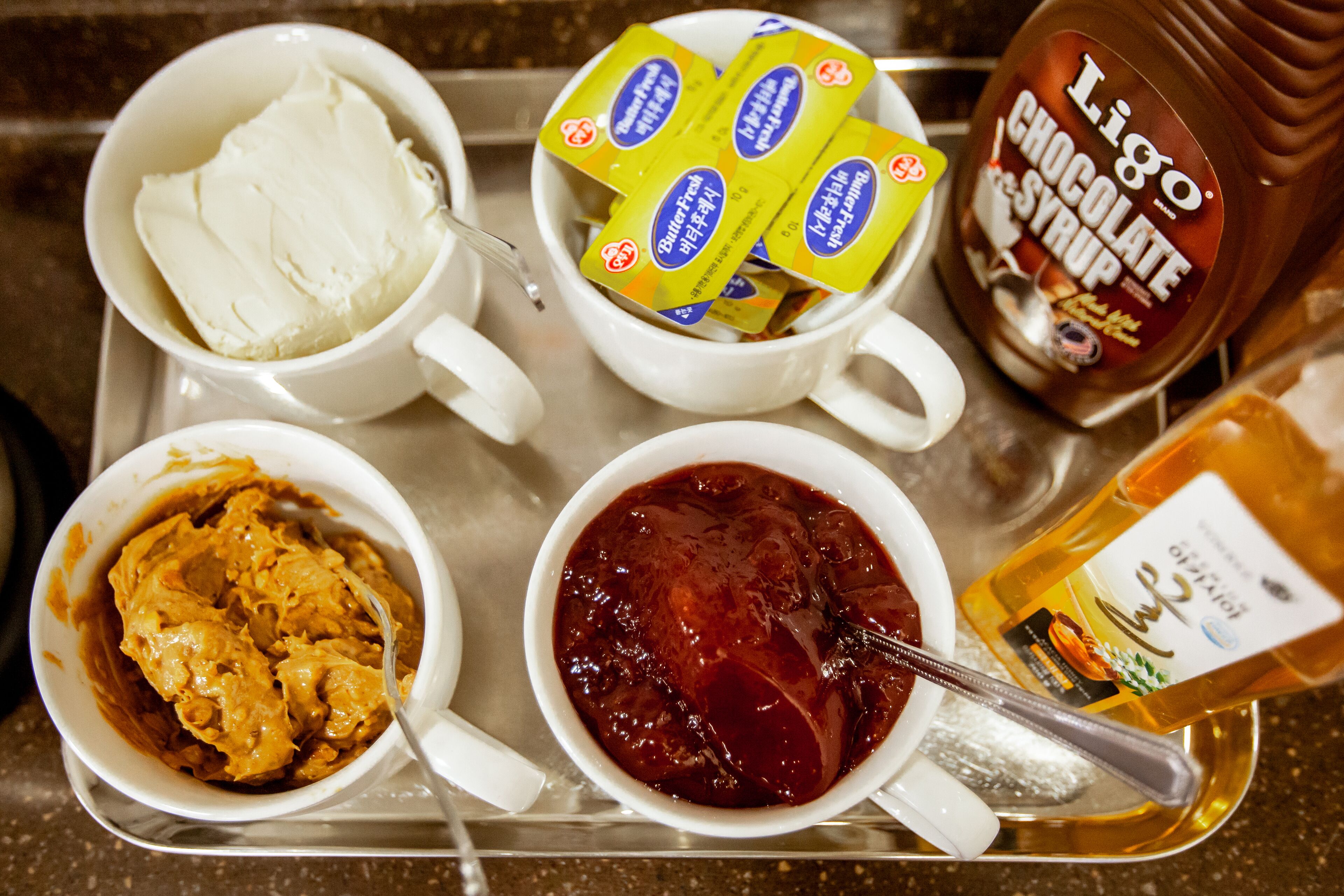 A tray with various food items including ice cream, chocolate syrup, and peanut butter.