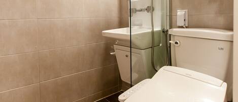 A modern bathroom with a toilet, shower, and glass-enclosed shower stall.