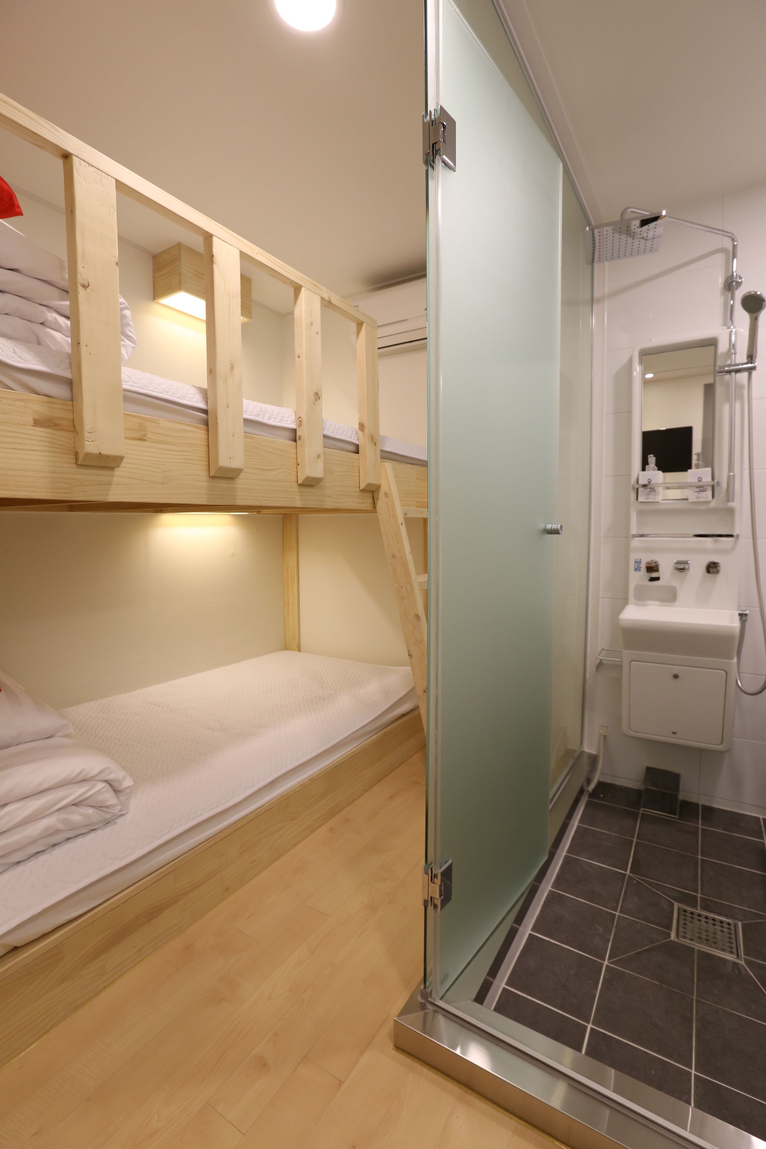 A bunk bed with a wooden frame and a glass shower enclosure.