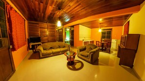 A cozy living room with wooden ceilings, a sofa, a coffee table, and a TV.