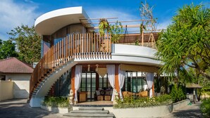 A modern house with a curved facade, a wooden staircase, and a balcony with plants. - The Akasha Seminyak Bali Boutique Hotel (Keroboken Kelod)