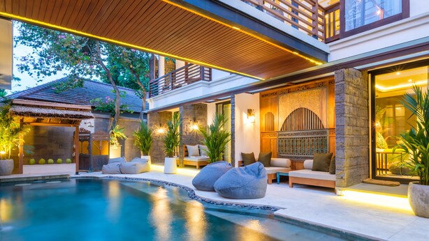A modern poolside area with a stone wall, seating, and a wooden deck. - The Akasha Seminyak Bali Boutique Hotel (Keroboken Kelod)
