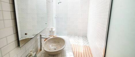 Un baño con un espejo grande, un lavamanos y una ducha.
