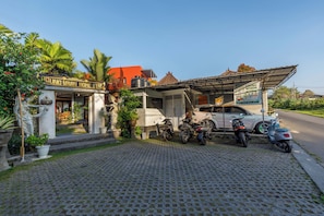 A building with a sign that reads 'GUNG WIWIN HOME STAY'. There are motorcycles parked in front, and a car is parked on the side. - Agung Wiwin Homestay (Munggu)