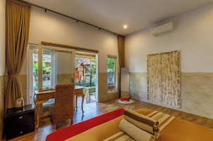 Habitación de hotel con cama, escritorio, silla, alfombra roja y vista al exterior.
