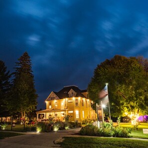 A large, yellow wooden house with a dark roof, surrounded by greenery and a paved driveway. - Lavender Fields Inn B&B (Calmar)