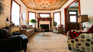 A cozy living room with a fireplace, wooden ceiling, and comfortable seating. - Lavender Fields Inn B&B (Calmar)