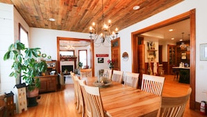 A dining area with a wooden table and chairs, a chandelier, and a potted plant. - Lavender Fields Inn B&B (Calmar)