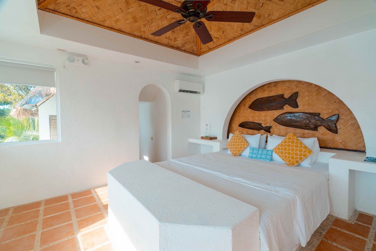 Ein Schlafzimmer mit einem Bett, einem Deckenventilator, einer Wandklimaanlage und einem Fenster.
