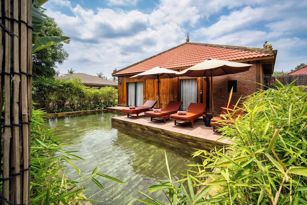 A wooden house with a pool, surrounded by greenery.