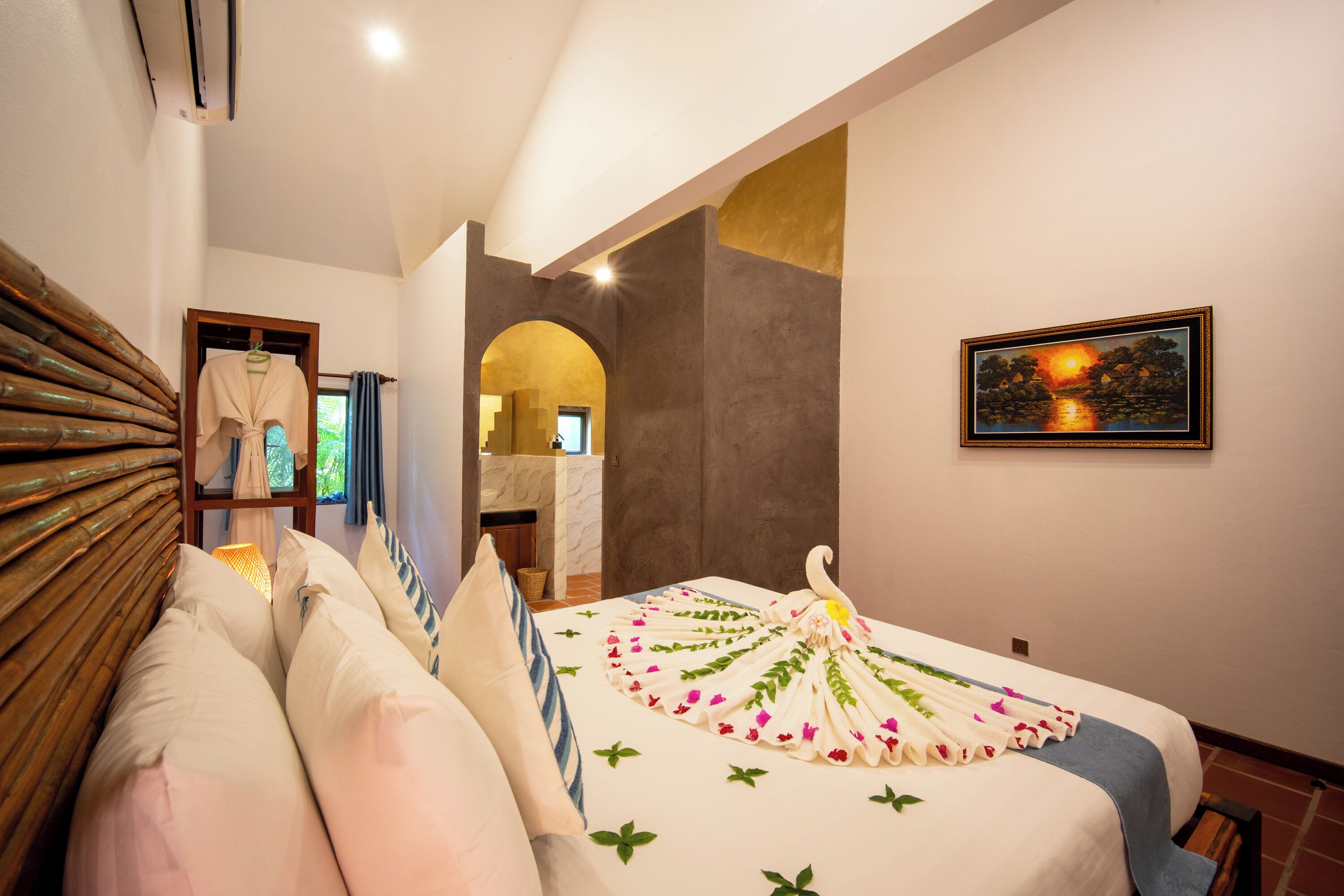 Quarto de hotel com uma cama, cabeceira de madeira, um quadro e vista para o exterior.