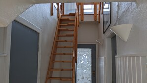 Eine Holztreppe führt zu einem Schlafbereich mit einem Fenster darüber.