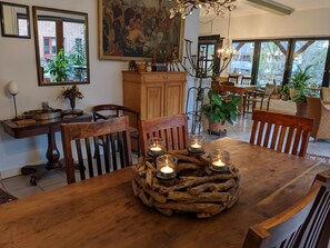 A dining area with a wooden table, chairs, and a centerpiece of candles in a log arrangement.