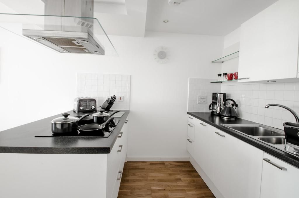 Una cocina moderna con armarios blancos, encimera negra y una campana extractora de acero inoxidable.