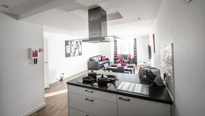 Een moderne keuken met een centraal eiland, een zithoek met een bank en tafel, en een woonkamer met een bank en gordijnen.