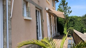 Un edificio con varias ventanas, un camino de piedra y una palmera al frente.