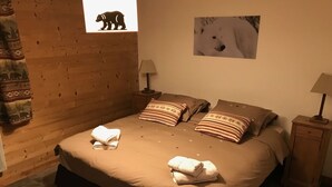 Une chambre confortable avec un grand lit, deux tables de chevet et un tableau représentant un ours accroché au mur.