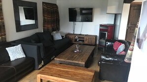 Un salon doté d’un grand téléviseur, d’une table basse en bois et de canapés en cuir noir.