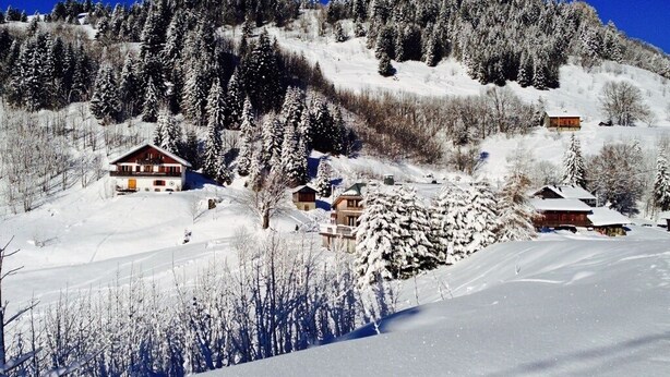 Une montagne enneigée, parsemée de chalets, sous un ciel bleu et dégagé.