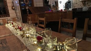 Une table à manger dressée avec des verres, des assiettes et des couverts, décorée de guirlandes lumineuses et d’ornements.