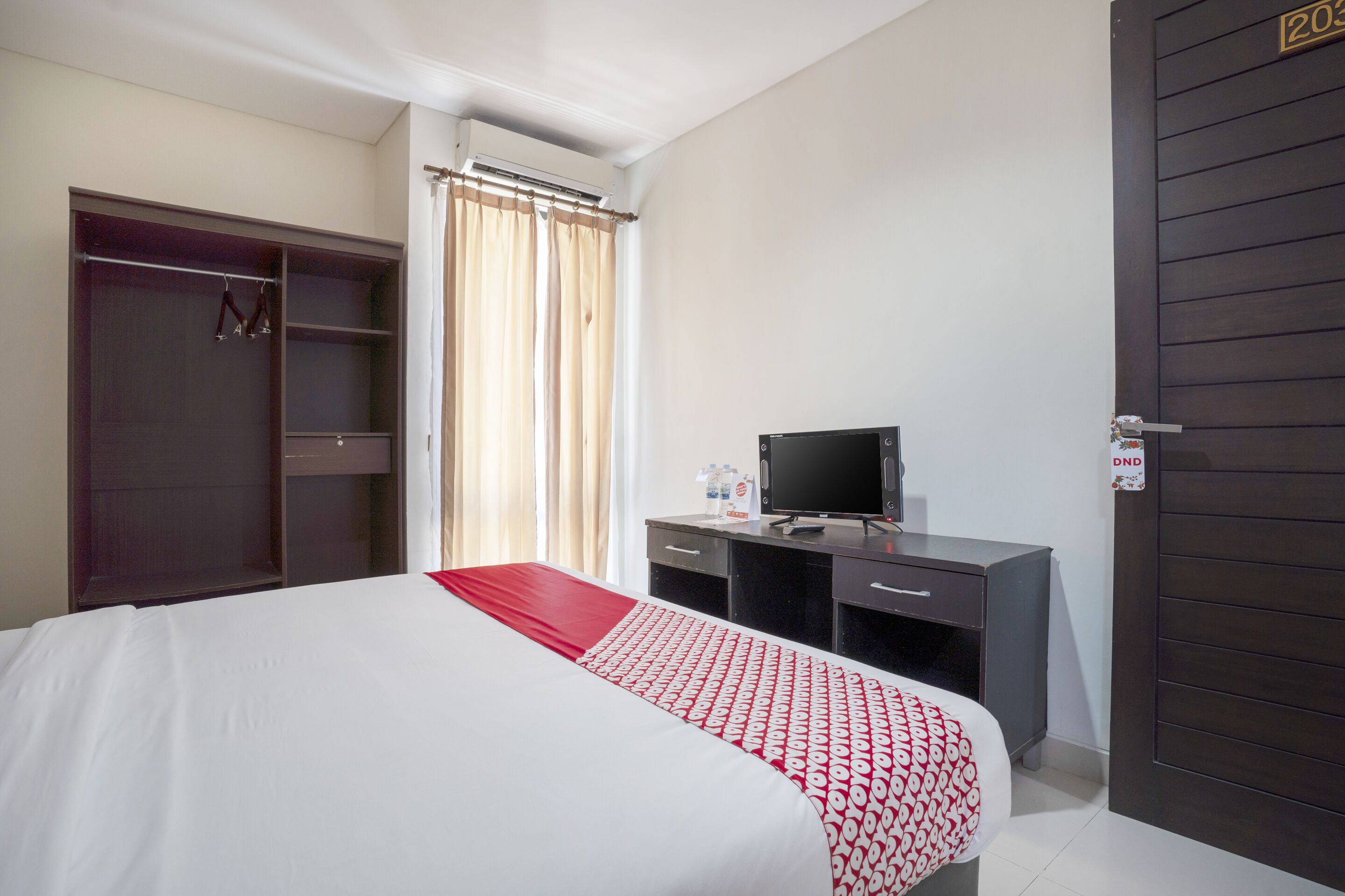 A hotel room with a bed, a desk, a television, and a wardrobe.