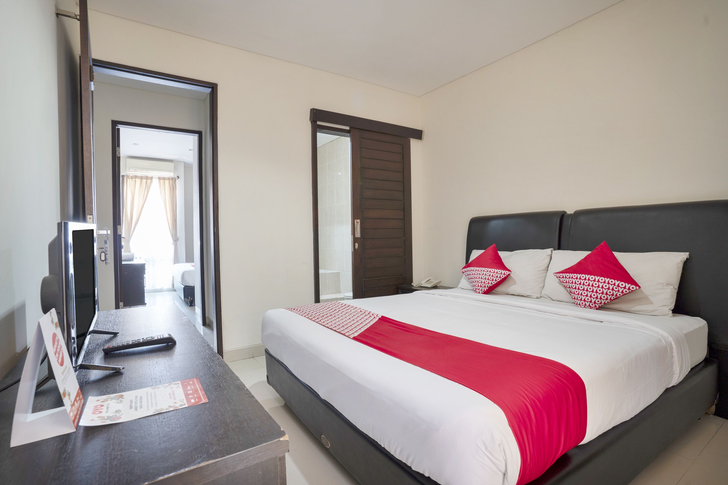 A hotel room with a bed, a desk, and a mirror.