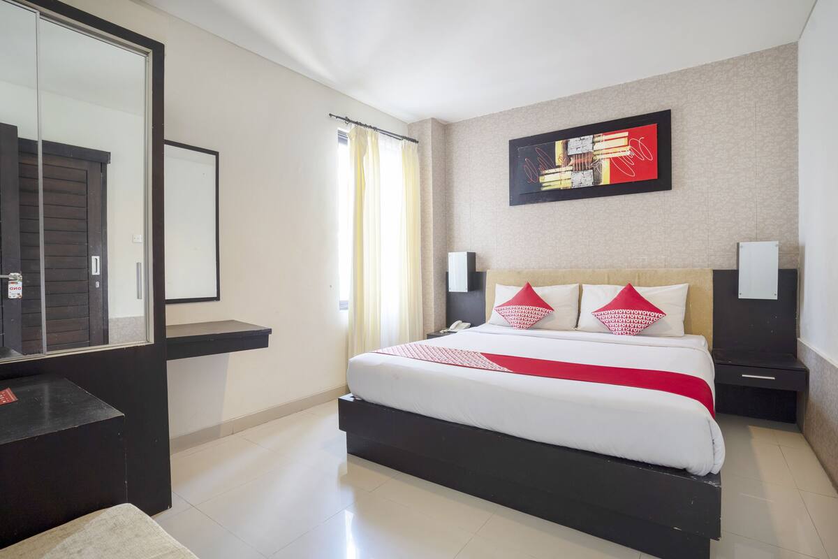 Une chambre d’hôtel moderne dotée d’un grand lit, d’un bureau, d’un miroir et d’une œuvre d’art accrochée au mur.
