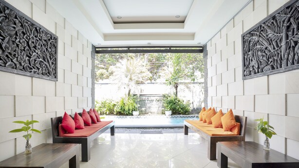 A modern lobby with two sofas, a reception desk, and a decorative wall. - Hotel O Anika Guest House (Tuban)