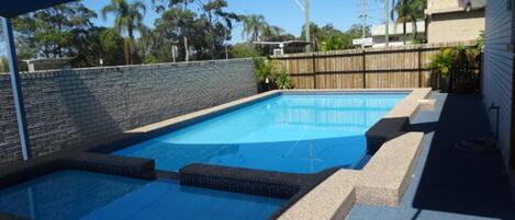A rectangular swimming pool with a stone border and a stone deck area.